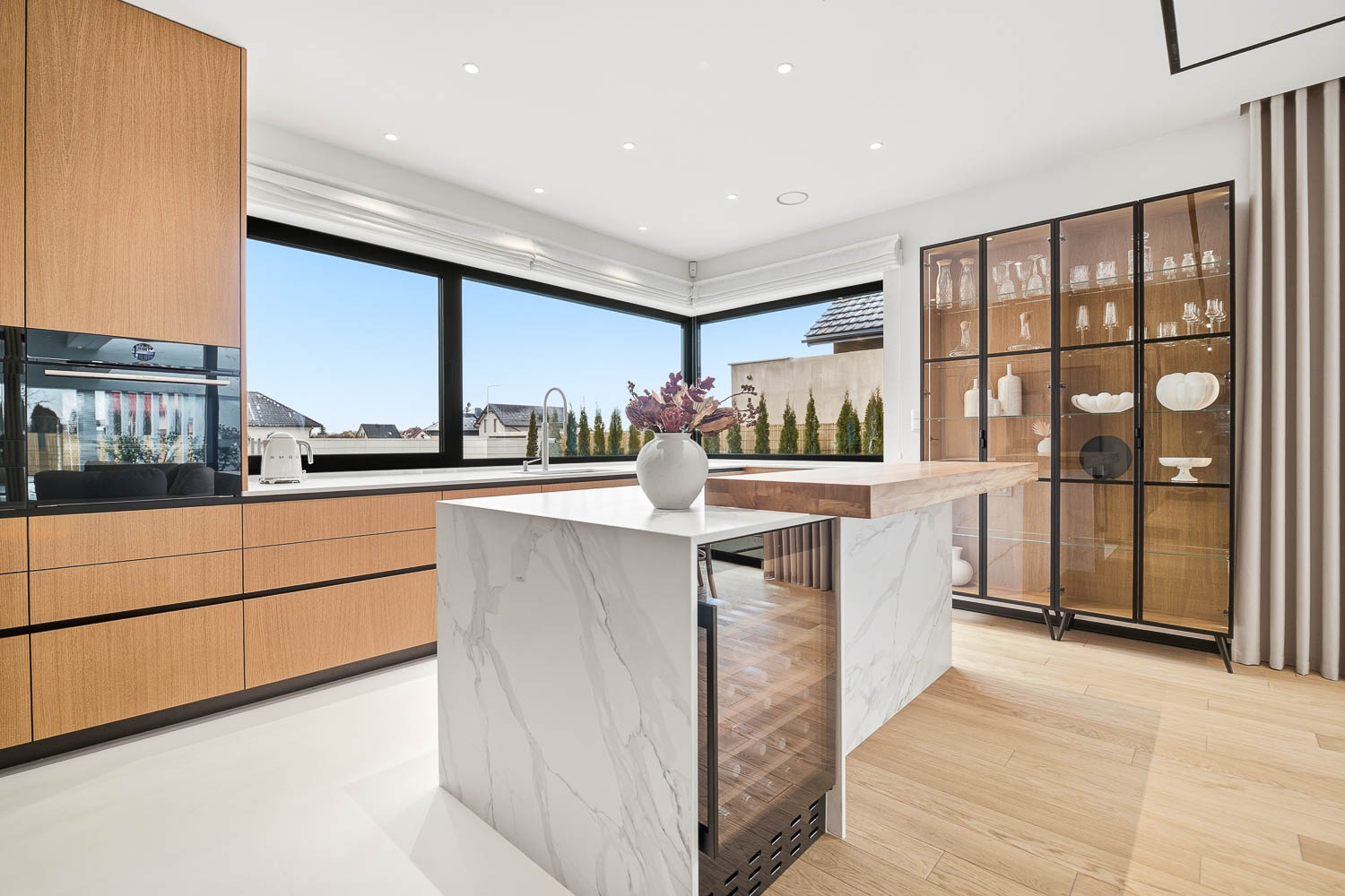 Nowoczesna kuchnia z marmurową wyspą i dużym przeszkleniem, wykonana przez fotografa wnętrz Grafoto we Wrocławiu